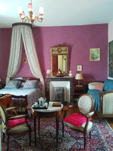 - une chambre avec des murs violets, un lit et une cheminée dans l'établissement Les Cèdres, à Montaigu-Vendée