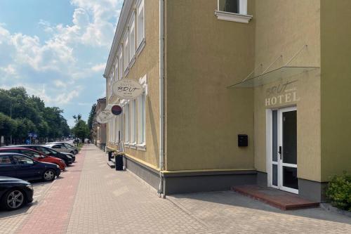 a building with cars parked on the side of a street at Brut Wine Hotel in Zarasai