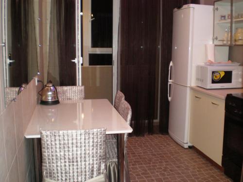 a kitchen with a white table and a refrigerator at Apartments NEW in Mykolaiv