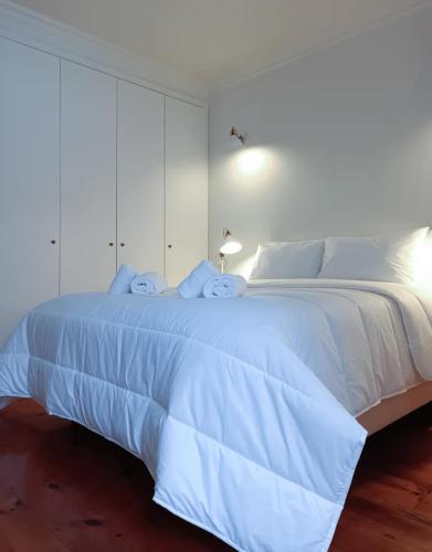 a white bedroom with a large white bed with white cabinets at Apartamentos Ázera - Lígia Ázera in Praia da Vitória