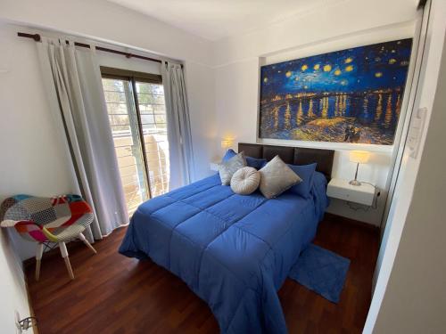 a bedroom with a blue bed with a painting on the wall at Patio San Ignacio in San Juan