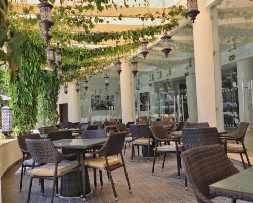 un restaurante con mesas, sillas y plantas en Kilua Beach Resort, en Mombasa