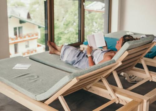 a man laying in a chair reading a book at Hotel Blü Gastein in Bad Hofgastein