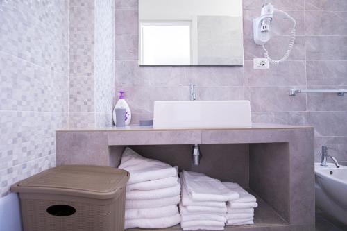 a bathroom with a sink and a pile of towels at Donnosanto Residence Pantanagianni in Torre Santa Sabina