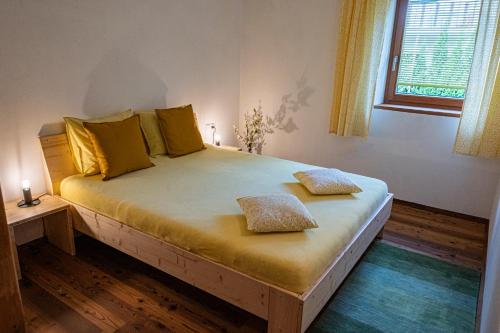 una camera da letto con un letto con cuscini gialli e una finestra di Haus18. 4 a Sluderno