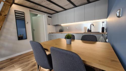 cocina y comedor con mesa de madera y sillas en Apartament Parkowy Antresola en Gniezno