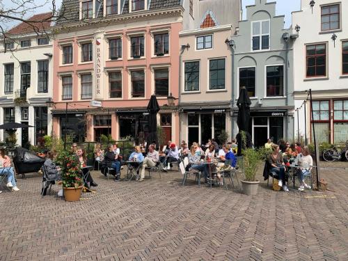 a group of people sitting in chairs in front of buildings at Daen’s Greenhouse in Utrecht