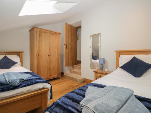 a bedroom with two beds and a mirror at Carrock Cottage in Dalston