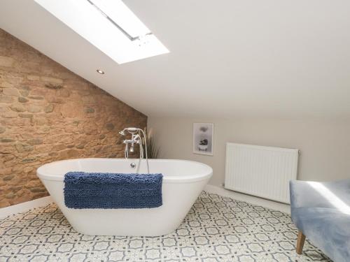 a white bath tub in a room with a brick wall at Carrock Cottage in Dalston