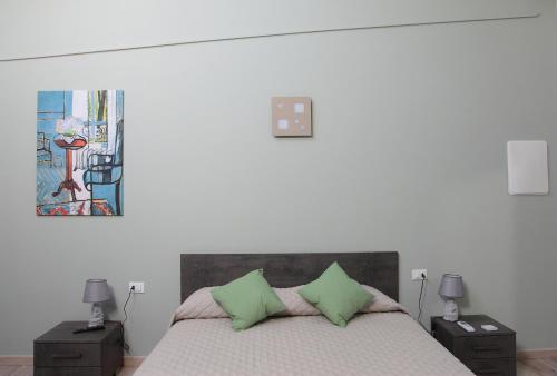 a bedroom with a bed with two green pillows at La CASA DEGLI ARTISTI in Tuscania