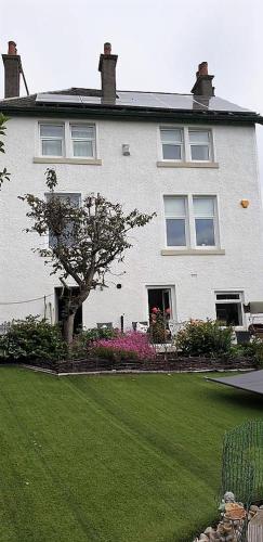 a white house with a tree in front of a yard at Glasgow Emo in Glasgow
