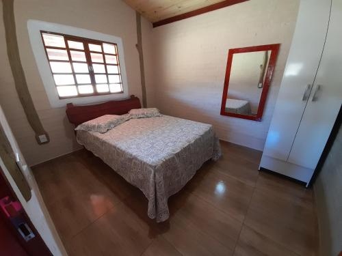 a small bedroom with a bed and a mirror at Chalé Recanto das palmeiras in São Thomé das Letras