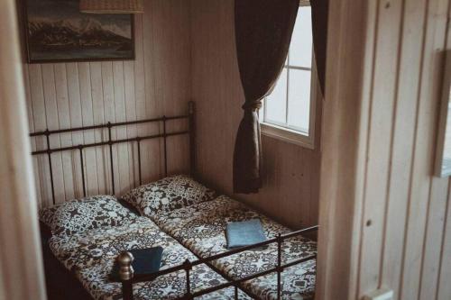 een klein bed in een kamer met een raam bij Cosy Cottage-Álfabakki-with hot tub in Stóri-Bakki