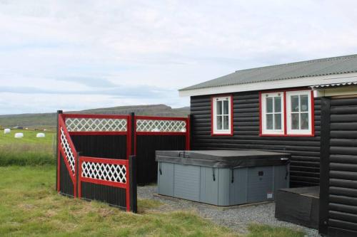 a small black house with a red fence next to it at Cosy Cottage-Álfabakki-with hot tub in Stóri-Bakki