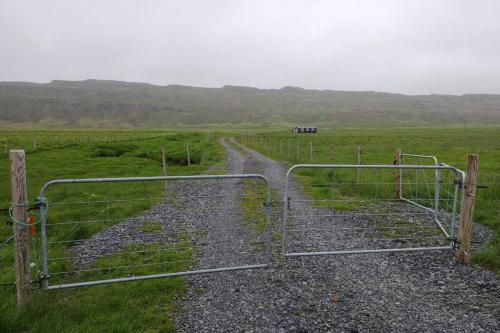 a gate in a field with a dirt road at Cosy Cottage-Álfabakki-with hot tub in Stóri-Bakki