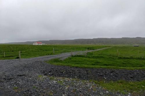 a dirt road in a field with a barn in the distance at Cosy Cottage-Álfabakki-with hot tub in Stóri-Bakki