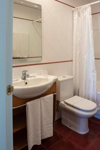 a bathroom with a sink and a toilet and a mirror at Hotel Faro de San Vicente in San Vicente de la Barquera