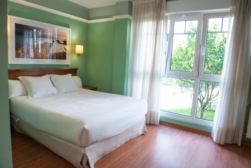 
a white bed sitting in a bedroom next to a window at Hotel Faro de San Vicente in San Vicente de la Barquera

