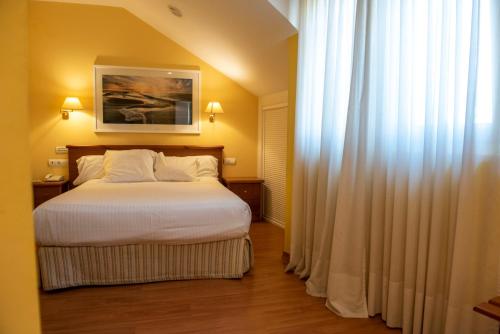 a bedroom with a bed and a window with curtains at Hotel Faro de San Vicente in San Vicente de la Barquera