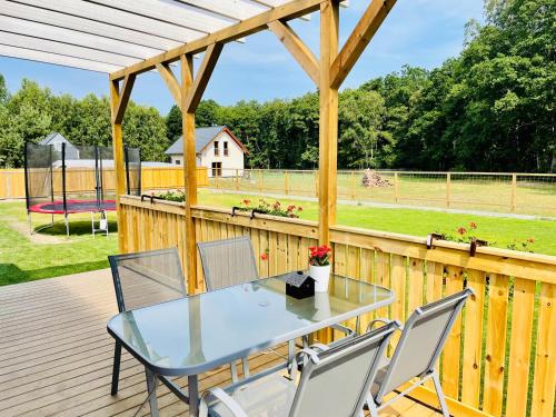 a patio with a glass table and chairs on a wooden deck at Czerwony Domek in Sasino