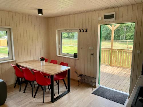 a dining room with a table and red chairs at Czerwony Domek in Sasino