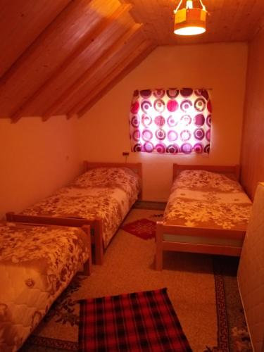 a bedroom with two beds and a window and a rug at Prenociste B&M - Lukomir in Lukomir