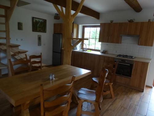 a kitchen with a wooden table and wooden chairs at Serce Beskidu Niskiego Myscowa in Krempna