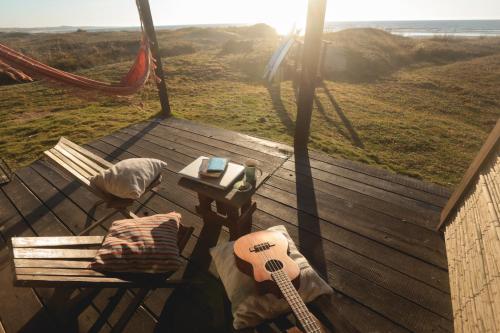 a guitar and a chair on a deck with a hammock at Ventanas al Mar in Cabo Polonio
