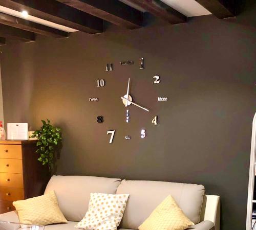 a clock on a wall next to a couch at Ca' Memi - Relaxing Stay in Chioggia in Chioggia