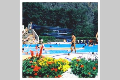 Un homme se promène dans une piscine avec des gens dans l'établissement L'edelweis, au Bourg-dʼOisans