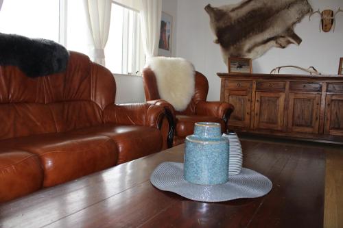 a living room with a leather couch and a blue candle on a table at Stóri-Bakki Guesthouse-with hot tub in Egilsstadir