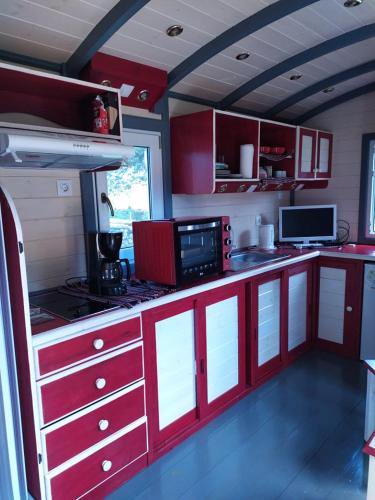 - une cuisine avec des placards rouges et blancs dans une pièce dans l'établissement La Roulotte de Francine, à Chazeuil