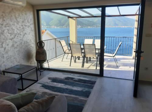 ein Wohnzimmer mit einem Balkon mit einem Tisch und Stühlen in der Unterkunft Martin Lux Apartment in Krasići
