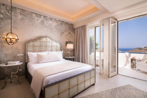 a bedroom with a large bed and a balcony at Ydor Hotel & Spa in Vourkari