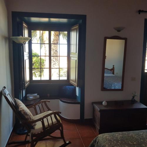 ein Schlafzimmer mit einem Stuhl, einem Spiegel und einem Bett in der Unterkunft Casa Pardelo in Fuencaliente de la Palma