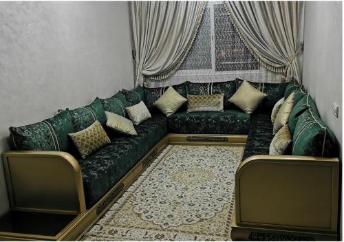Superbe appartement F3 tout confort في أغادير: أريكة خضراء في غرفة معيشة مع ستائر