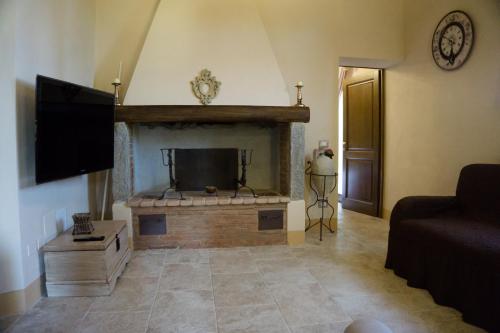 sala de estar con chimenea y TV de pantalla plana en Antica Casa del Glicine, en Poggibonsi