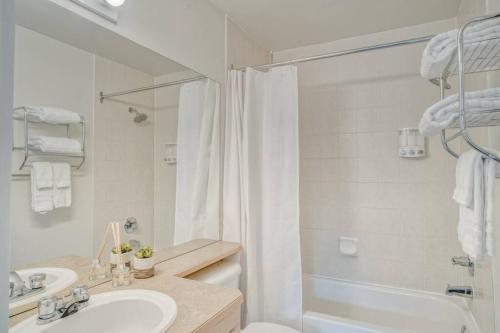 Un baño blanco con lavabo y ducha. en Cozy 2 BR - King and Queen Condo Sleep up to 6 for WFH & Vacation, en Canmore
