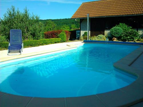 a large blue swimming pool with a chair and a house at Notre Rêve - Chambre d'hôtes in Marmoutier