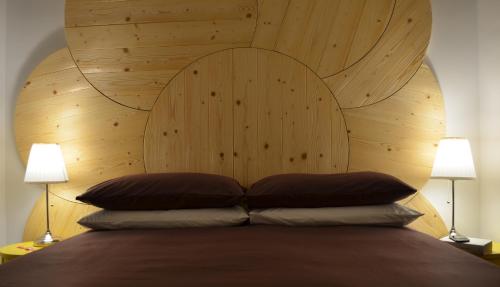 a bed with a wooden headboard with two lamps at Angelina Urban Lodge in Tolentino