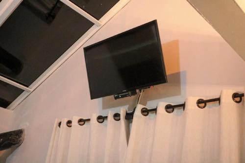a flat screen tv on a wall with curtains at Império Cabanas in Urubici
