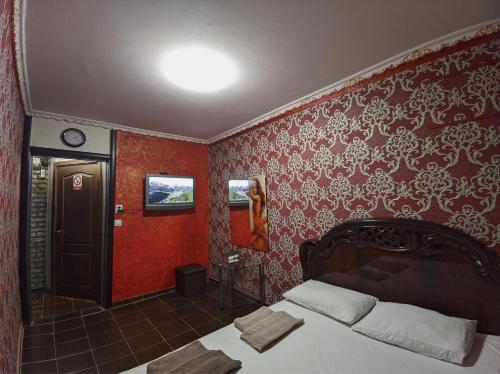 a bedroom with red walls with a bed and a clock at Смарт квартира на победе in Dnipro