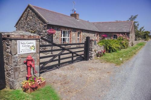 a stone building with a gate and a fence at Sally Gardens Cottage in Downpatrick