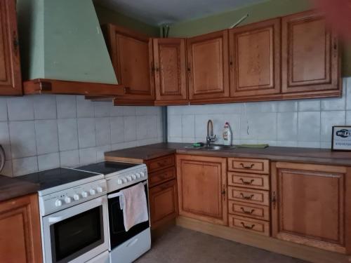 uma cozinha com armários de madeira e um forno de fogão branco em The Bunker hostel em Liepāja