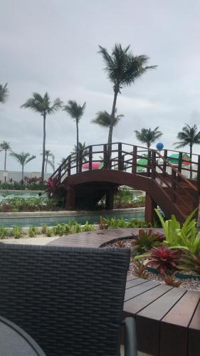 a wooden bridge in a park with palm trees at Salinas Exclusive Resort in Salinópolis