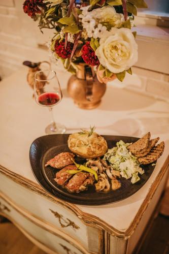 a plate of food on a table with a glass of wine at Hotel Coandi in Arad