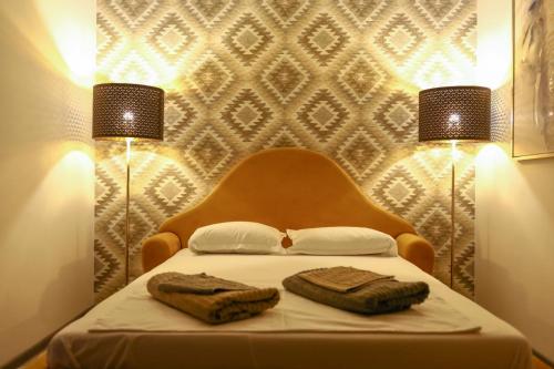 a bedroom with two towels on a bed with two lights at Colonial Touch Apartament in Braşov