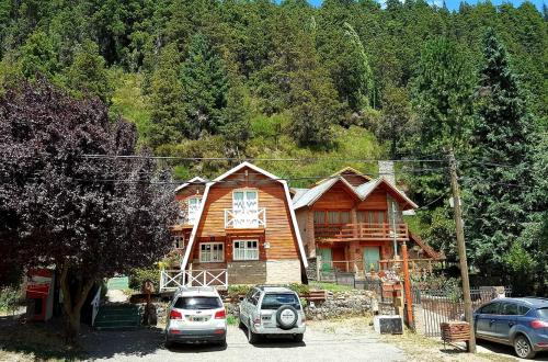 una casa de madera con dos coches aparcados frente a ella en Villa El Radal en San Martín de los Andes