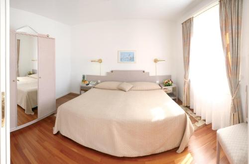 a white bedroom with a large bed and a window at Villa Sassa in Lugano