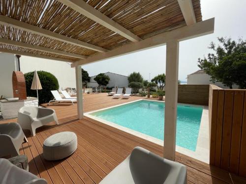 una piscina su una terrazza in legno con sedie di Dimora Ferralasco a Carloforte